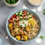 A colorful Mexican Grilled Chicken Bowl featuring sliced smoky chicken breast over brown rice, black beans, cherry tomatoes, corn, avocado slices, and a dollop of lime‑yogurt drizzle