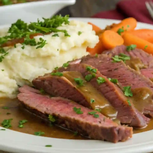 the Flavor 10 A Guide to Perfectly Braised Corned Beef 3 A plate of tender braised corned beef, served with a side of mashed potatoes and cabbage, garnished with parsley